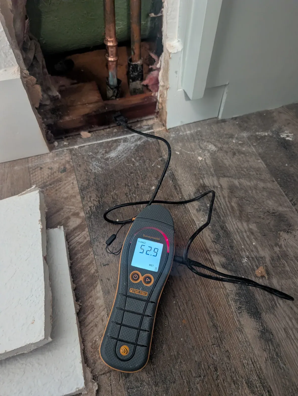 Protimeter moisture meter reading 52.9 percent WME at an opened wall during water damage inspection