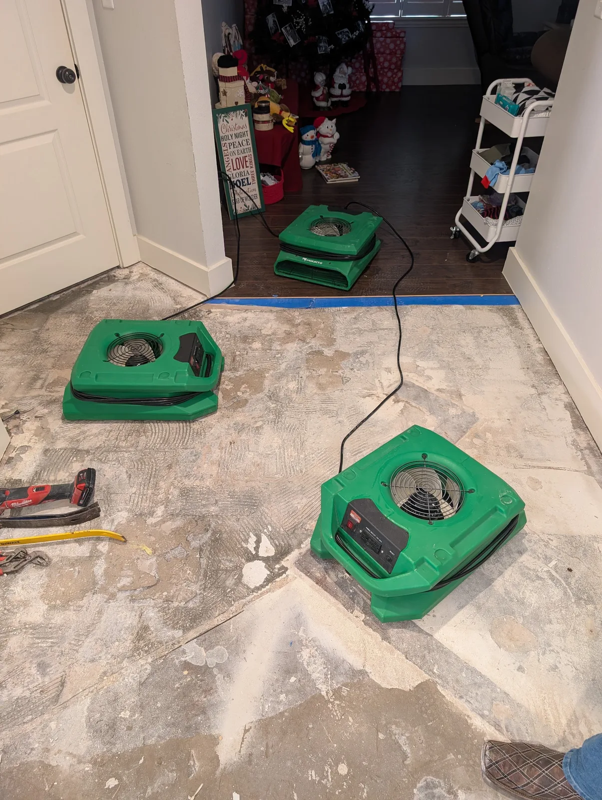 Air movers and an LGR dehumidifier drying a stripped slab in an occupied North Texas home